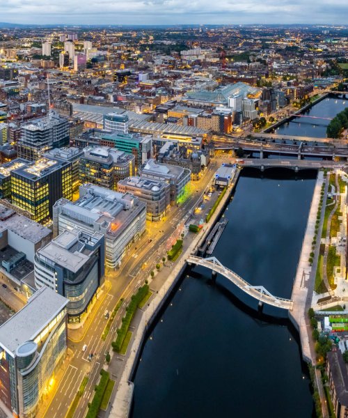 Glasgow United Kingdom aerial shot of modern buildings in the central area of the city with river and squigly bridge in the foreground in twilight